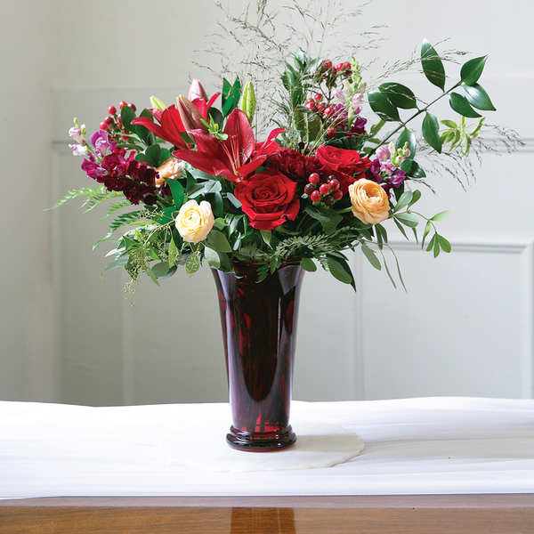 Red and peach flowers arranged in a tall glass vase
