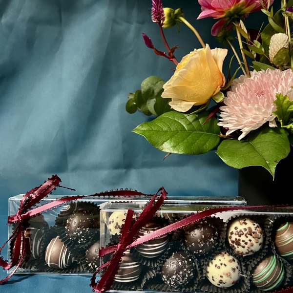 Gift set with mixed flower arrangement in a black vase and two boxes of assorted chocolate truffles