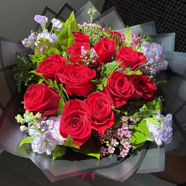 Bouquet of red roses with pale lavender flowers and black wrapping