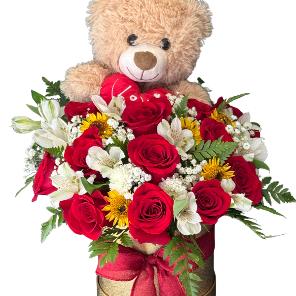 Teddy bear above a red and white flower arrangement in a round box