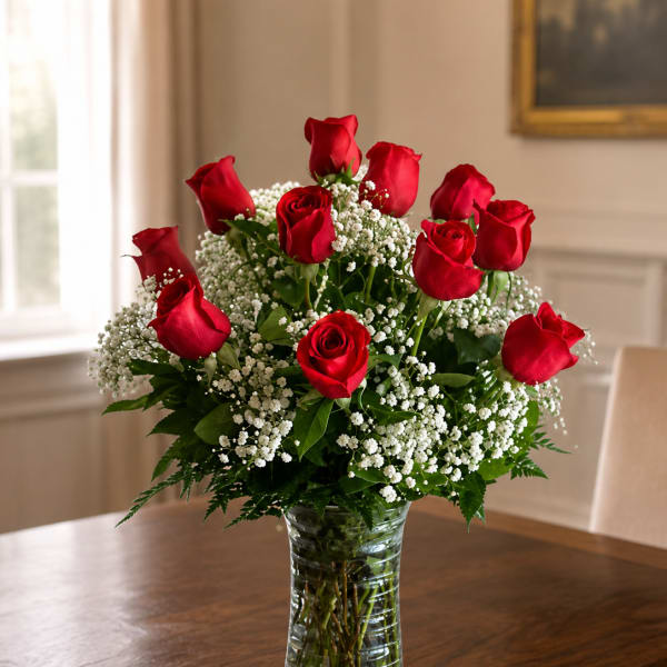 Red roses arranged in a clear glass vase with white filler flowers