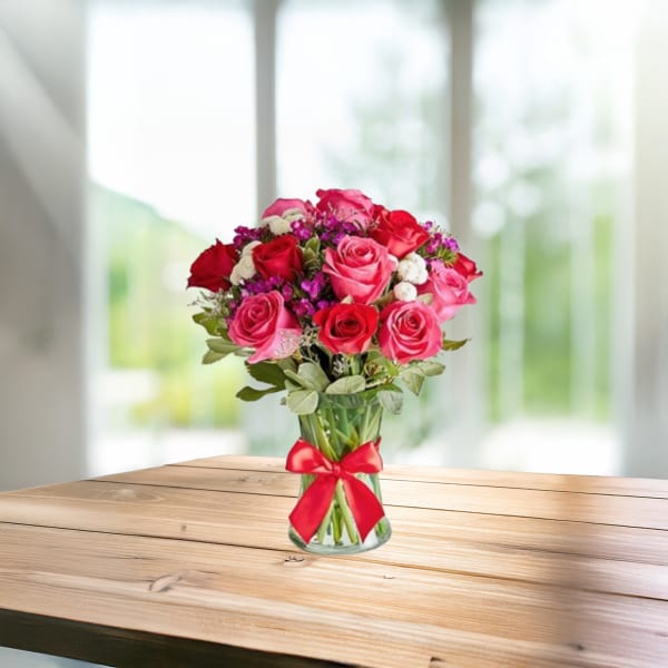 Bouquet of pink and red roses in a glass vase with a red ribbon