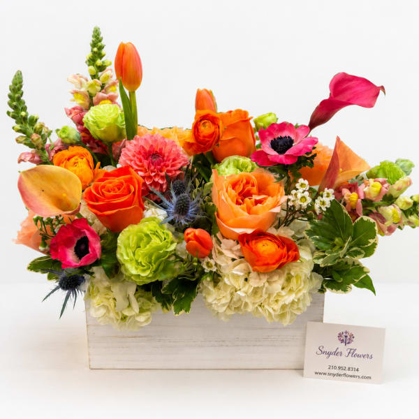 Bright mixed flower arrangement in a white wooden box