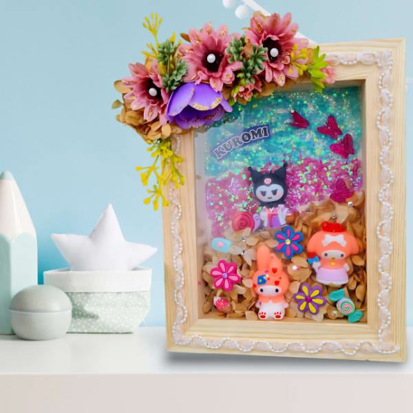 Decorative framed display with faux flowers and small cartoon figures