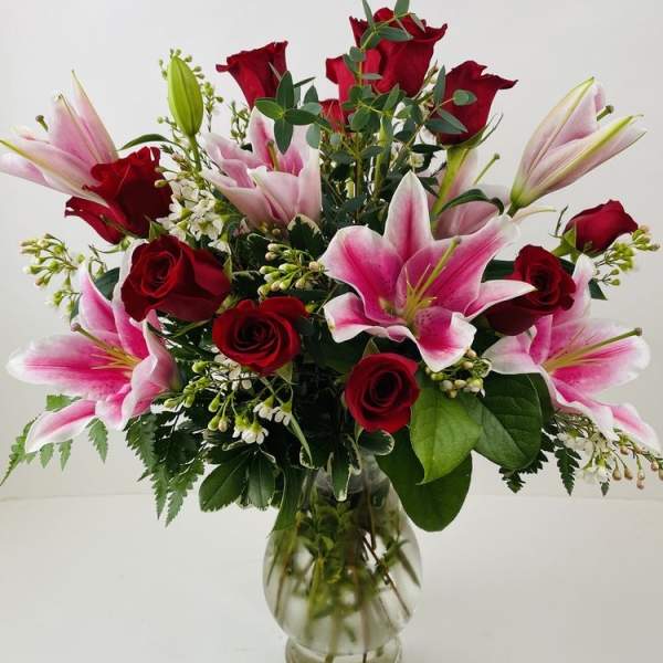 Red roses and pink lilies arranged in a clear glass vase