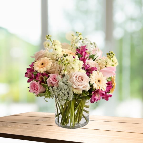 Mixed pink and white flowers arranged in a clear glass vase