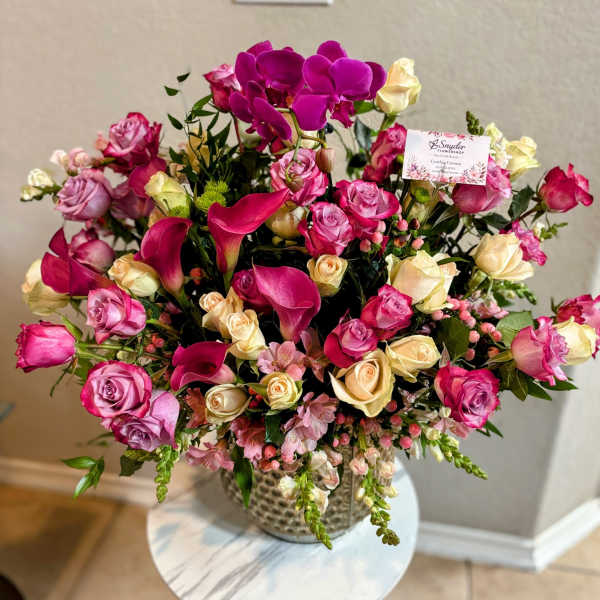 Pink and cream roses with magenta orchids in a vase