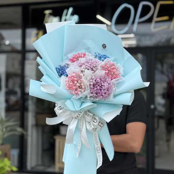 Bouquet of pastel baby’s breath wrapped in light blue paper with a ribbon