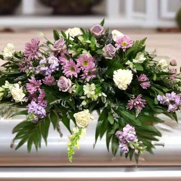 Lavender and white floral casket spray with greenery