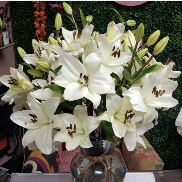 White lilies arranged in a glass vase with a twine tie