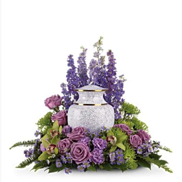 Purple floral arrangement around a white urn-shaped vase