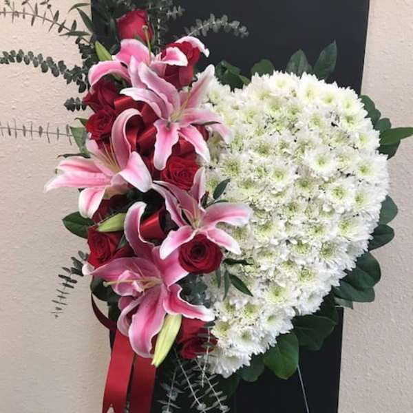 Heart-shaped floral spray with pink lilies, red roses, and white chrysanthemums