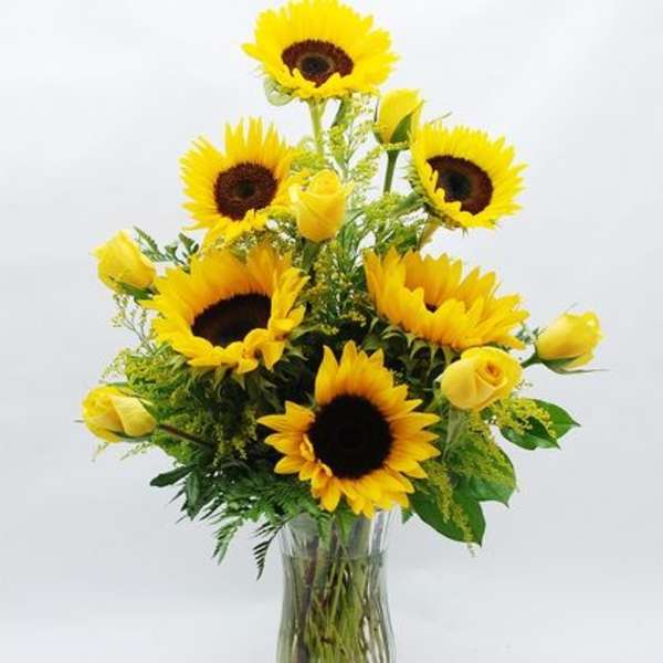 Sunflowers and yellow roses arranged in a glass vase
