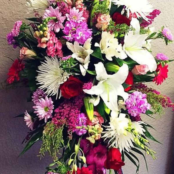 Tall standing floral spray with lilies, roses, and pink mixed blooms