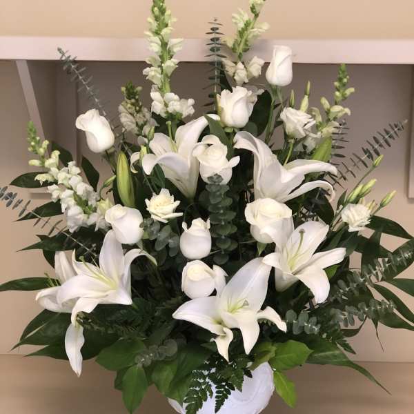 White lilies and roses arranged in a white vase