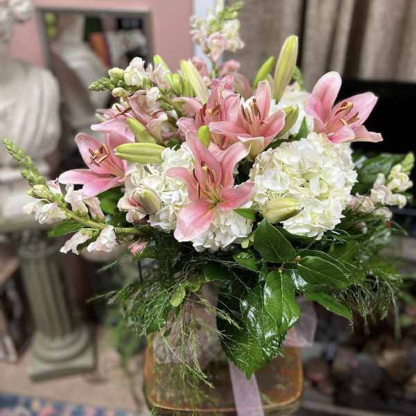 Pink lilies and white hydrangeas arranged in a glass vase