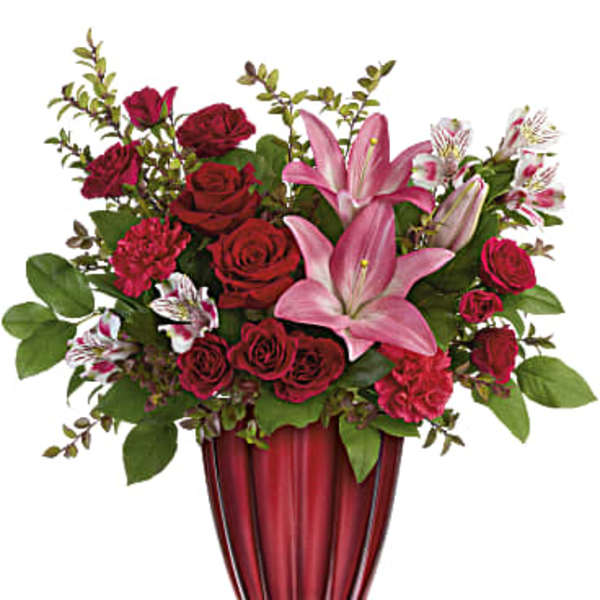 Red roses and pink lilies arranged in a red glass vase