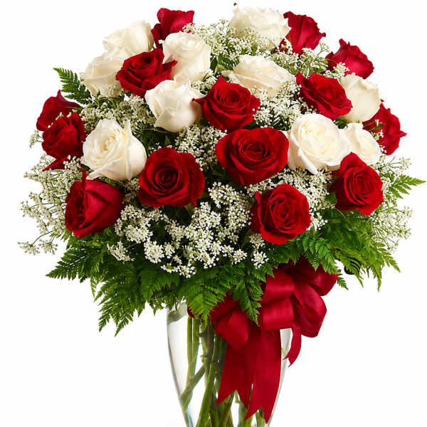 Red and white roses in a clear glass vase with a red ribbon