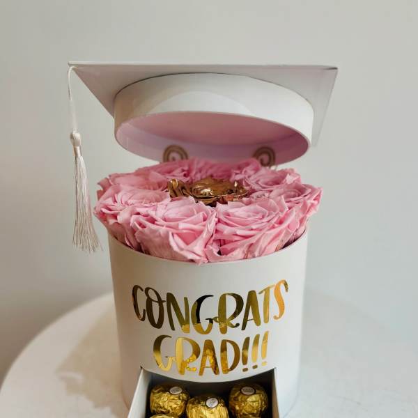 Pink roses in a white graduation gift box with chocolates