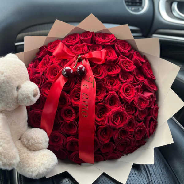 Round bouquet of red roses with a red ribbon and teddy bear