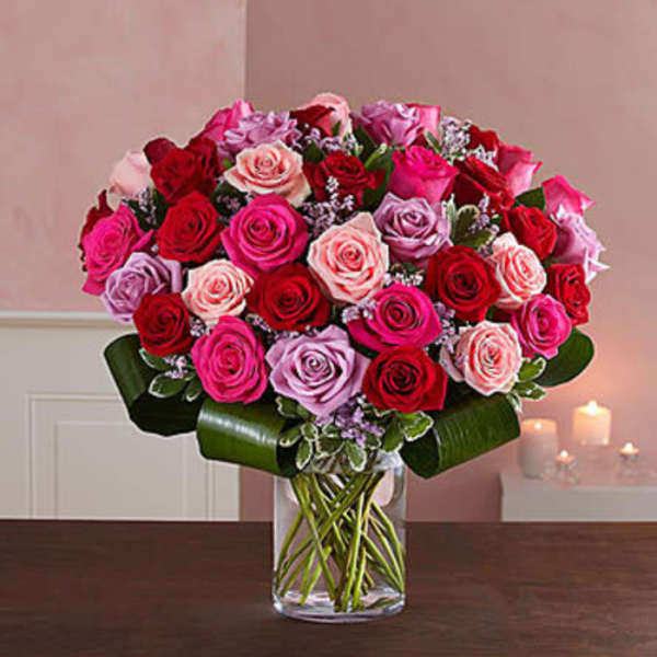 Bouquet of pink, red, and lavender roses in a clear glass vase