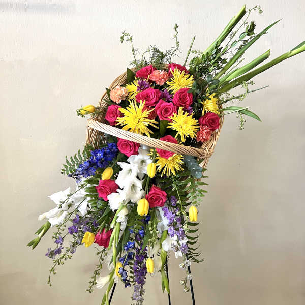 Large mixed flower basket on a stand with bright pink, yellow, white, and purple blooms