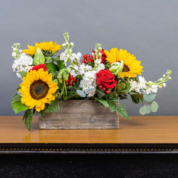 Sunflowers and red roses in a wooden box with white blooms
