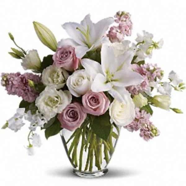 Bouquet of white lilies and pink roses in a clear glass vase