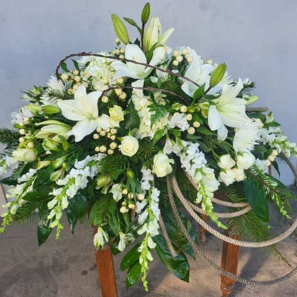 Large white floral spray with lilies and roses on a stand