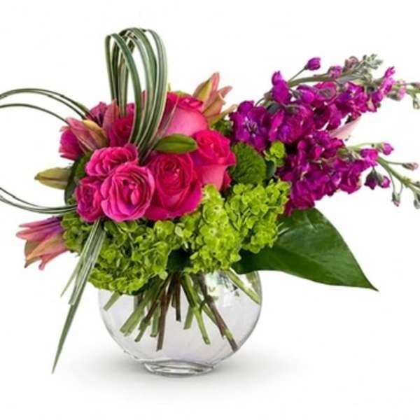 Pink roses and purple flowers in a clear glass vase