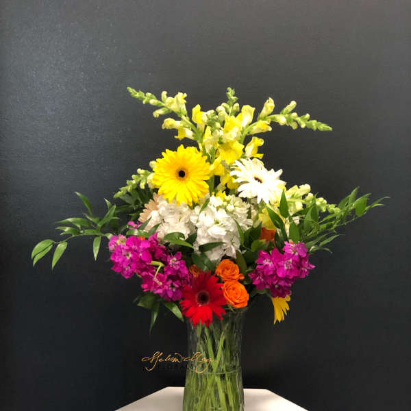Mixed bouquet in a glass vase with yellow, white, pink, and orange flowers