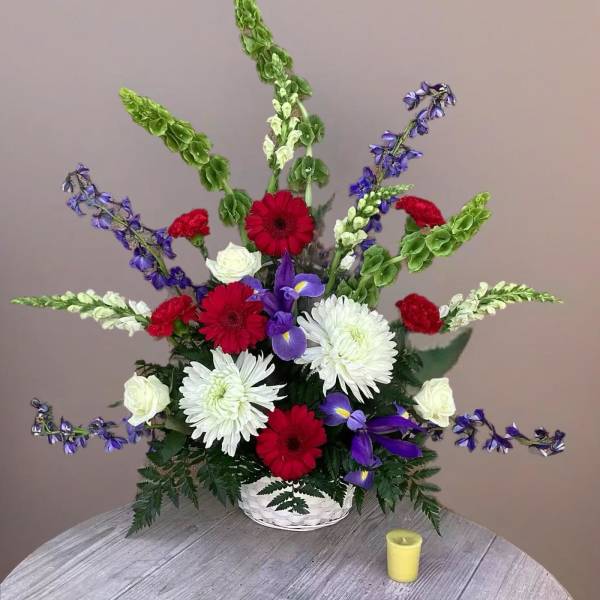 Red, white, and purple flowers in a white basket arrangement