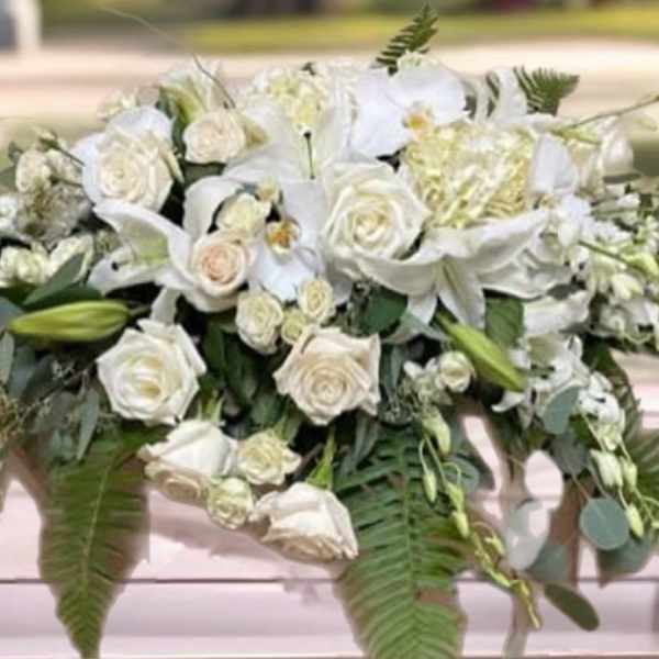 White floral casket spray with roses and lilies