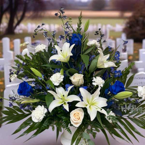 White lilies, blue roses, and white carnations in a white vase