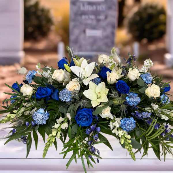 Blue and white floral casket spray with roses and lilies