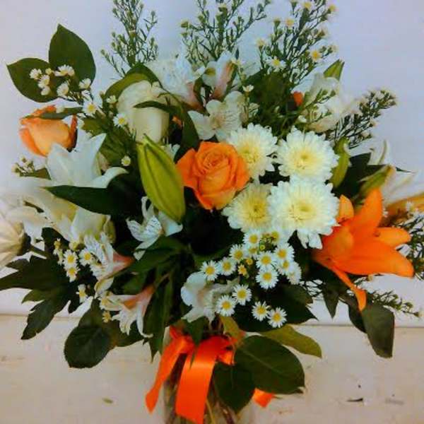Bouquet of orange and white flowers in a glass vase with an orange ribbon