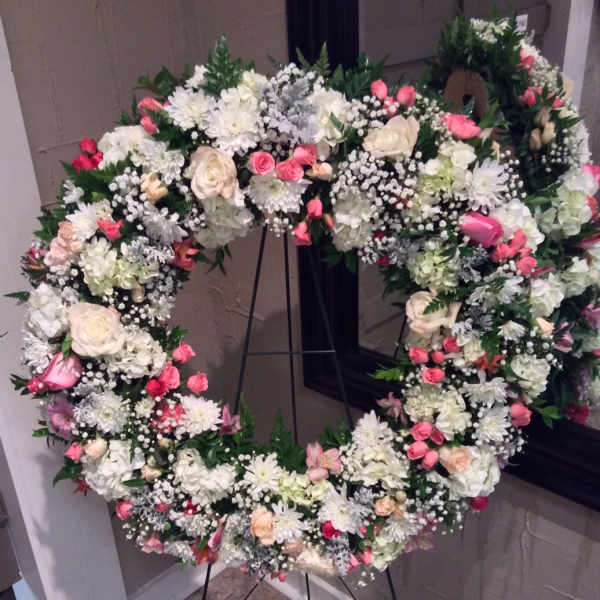 Large heart-shaped floral wreath on a stand with white and pink flowers