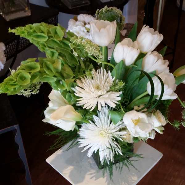 White tulips and spider mums arranged with green blooms in a vase.