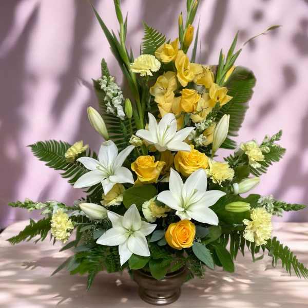 Yellow roses and white lilies arranged in a bronze vase