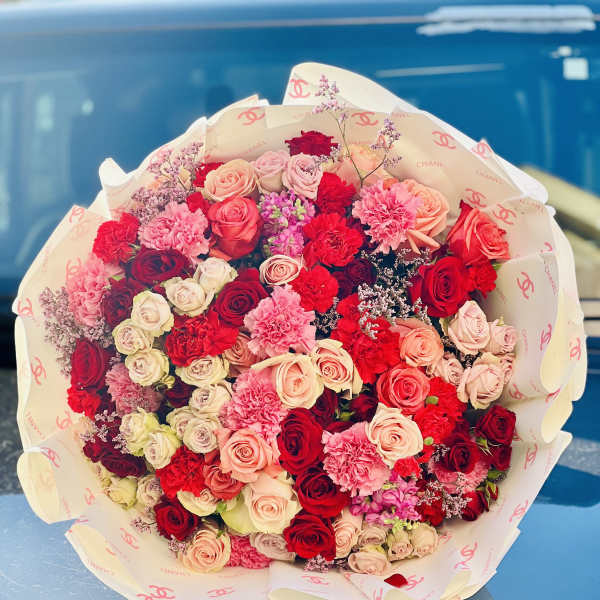 Large bouquet of pink and red roses with carnations in branded wrapping