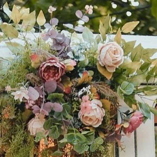 Floral garlands with pink and cream flowers drape over a white structure.