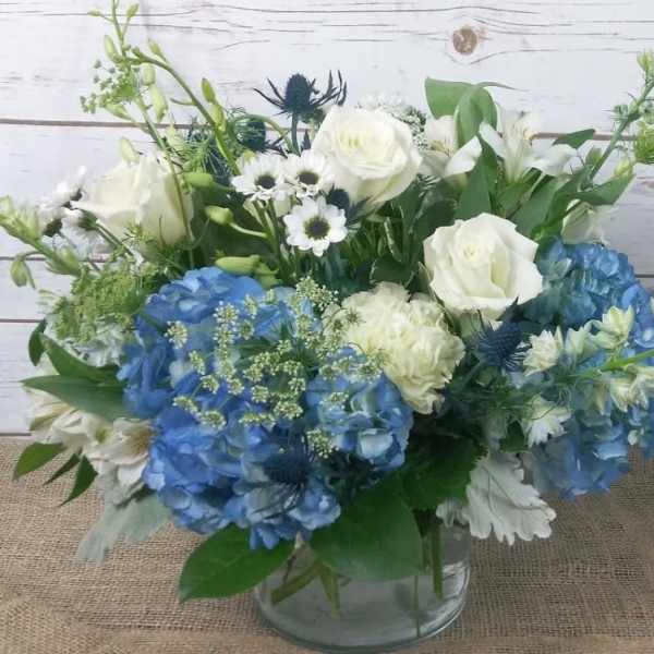 Blue and white flower arrangement in a clear glass vase