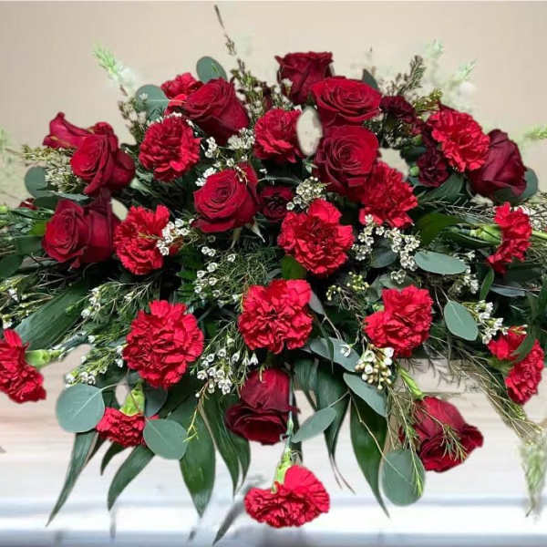 Red roses and carnations arranged in a low casket spray