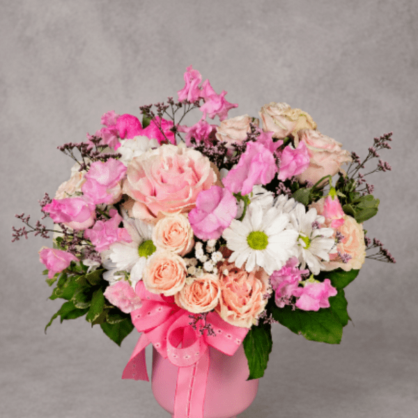 Pink and peach bouquet in a pink vase with a ribbon
