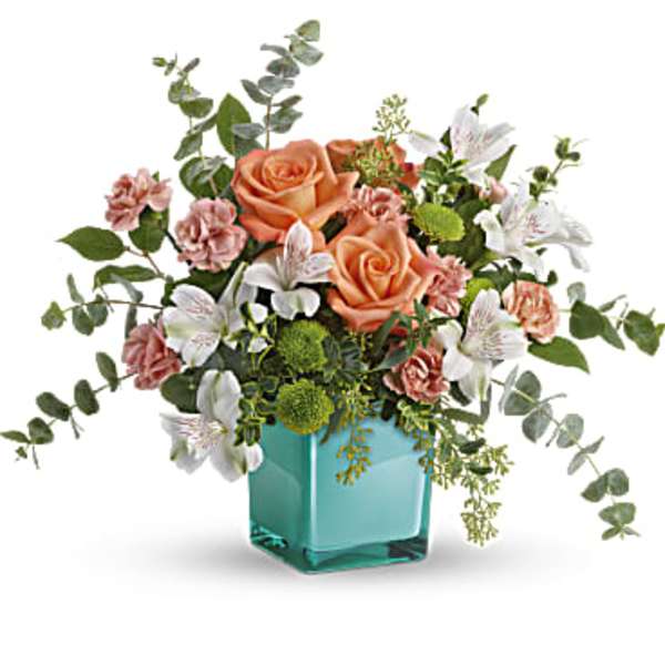 Peach roses and white lilies in a turquoise glass vase