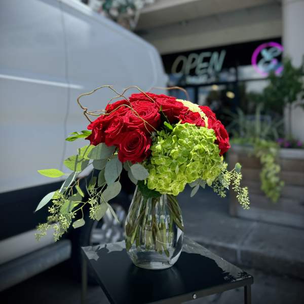 Red roses and green hydrangea in a glass vase