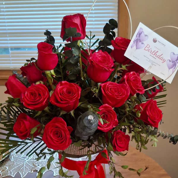 Bouquet of red roses in a clear glass vase with a birthday card