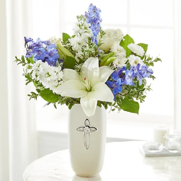 White lilies and blue flowers arranged in a tall vase