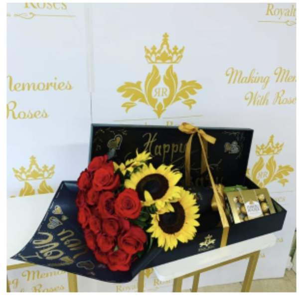 Red roses and sunflowers arranged in a black gift box with chocolates