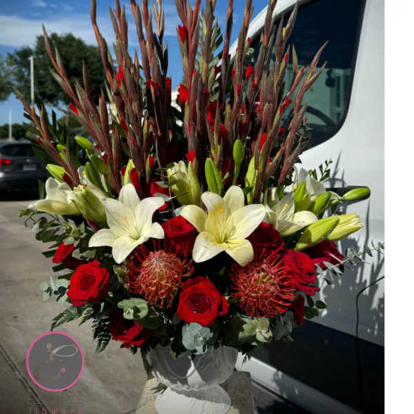 Tall red and white floral arrangement in a white vase
